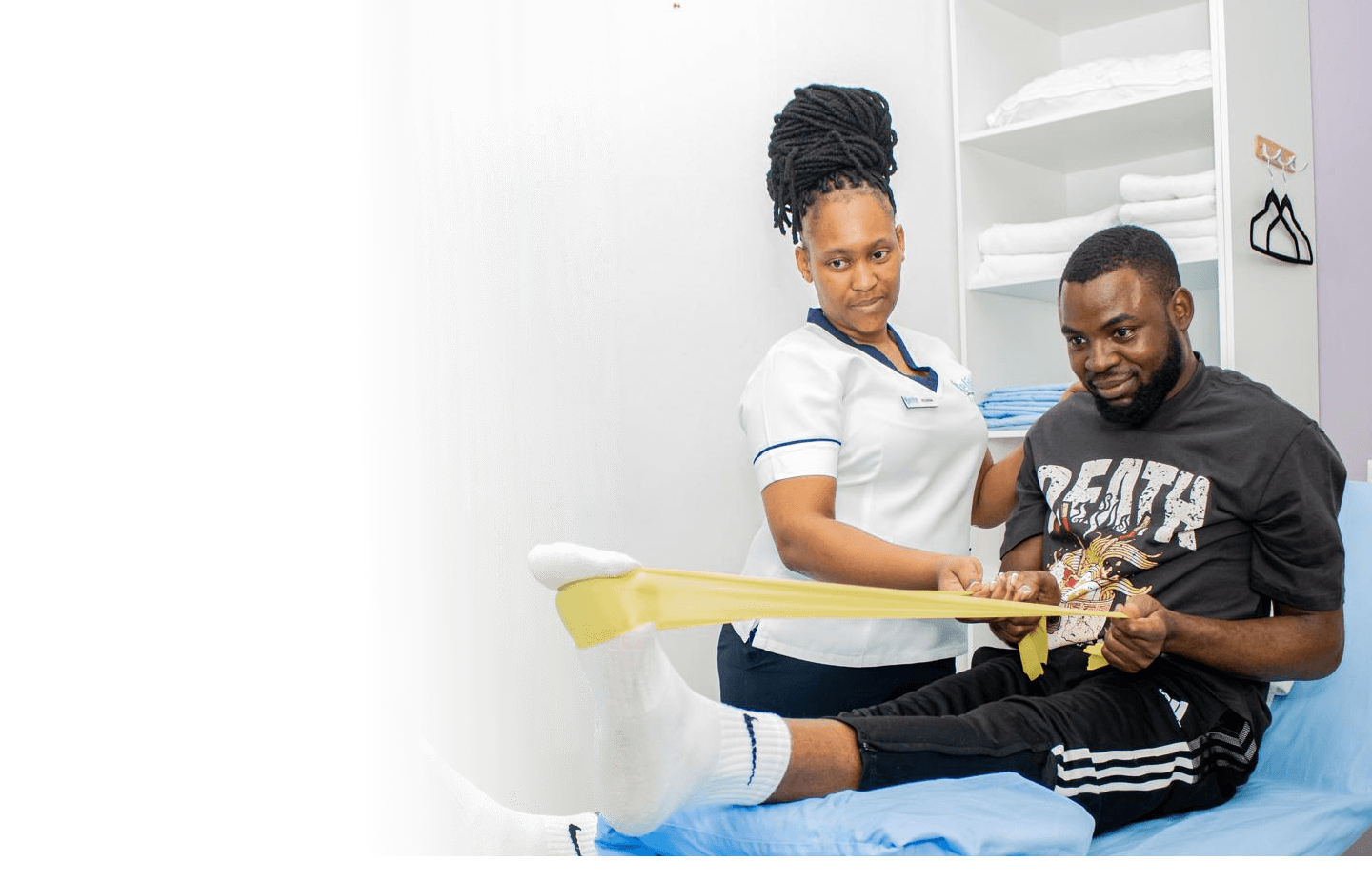 An Elite Physiotherapy clinician guiding a patient through a resistance-band rehabilitation exercise